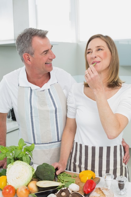 Cheerful couple preparing food together in kitchen