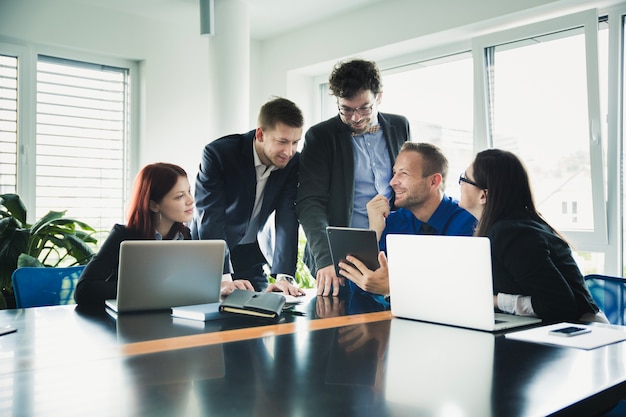 Photo cheerful coworkers at table with gadgets