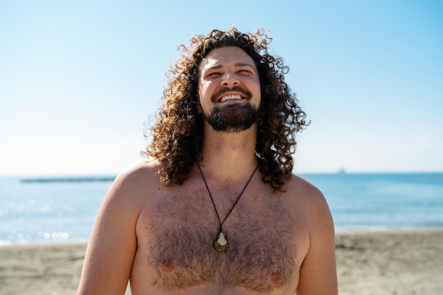 Cheerful curly man relaxing on the beach during sunny summer day