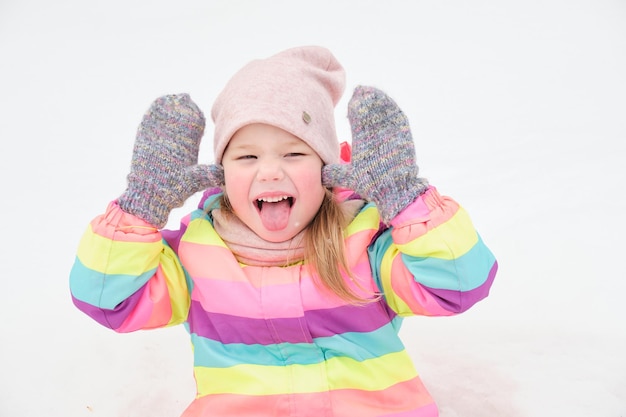 Cheerful cute girl 5 years old plays in the snow and makes funny faces