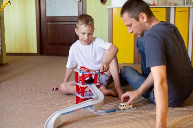 Cheerful dad plays with a cute boy at home in cars