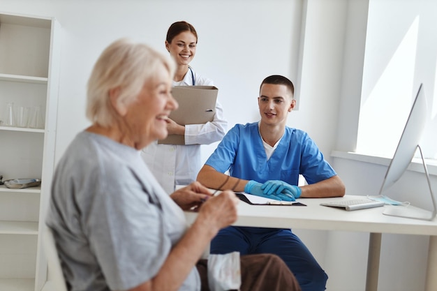 Cheerful elderly woman in the hospital talking to a nurse and a doctor consultation