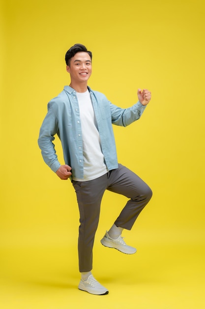 Cheerful excited man standing isolated over yellow background celebrating success