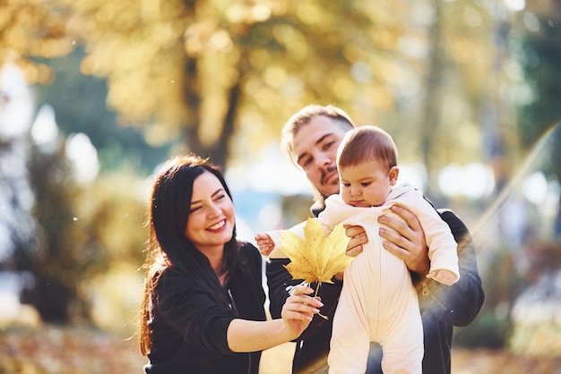 Cheerful family having fun together with their child in beautiful autumn park.