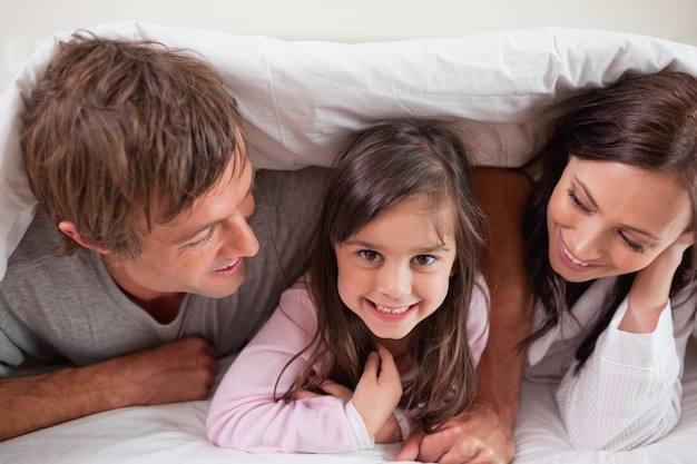 Cheerful family lying under a duvet