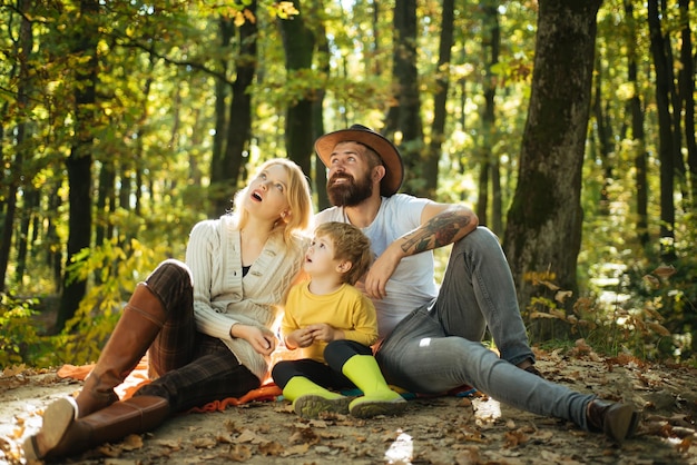 Cheerful family sitting on the grass during a picnic in a park there is a basket with meal and toys