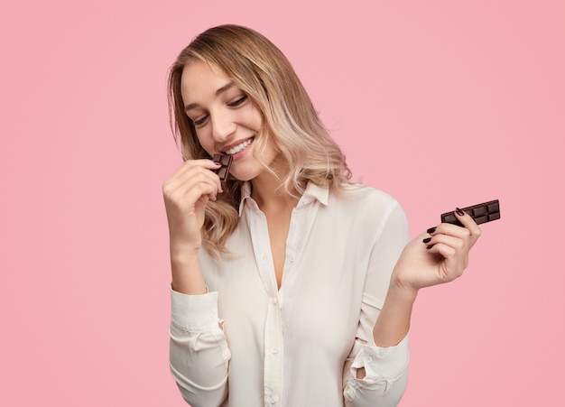 Cheerful female eating chocolate