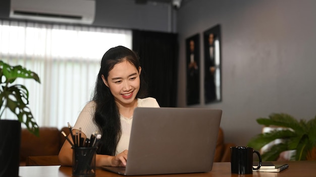 Cheerful female freelancer using laptop at her contemporary home office