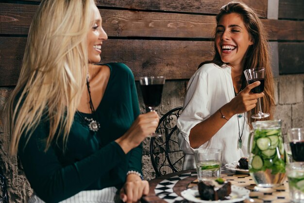 Photo cheerful female friends having red wine at outdoors restaurant during night