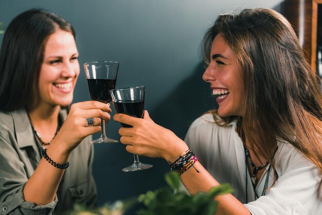 Photo cheerful female friends toasting wineglasses in restaurant