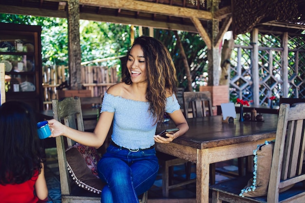 Cheerful female sitting in cafe with little daughter