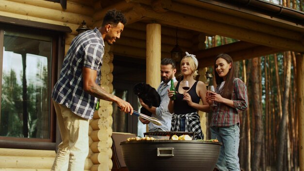 Cheerful friends having rest on grill party outdoors Guys clinking glasses