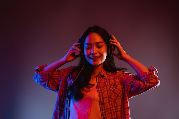 Cheerful girl enjoying music using headphones with two hands holding headphones