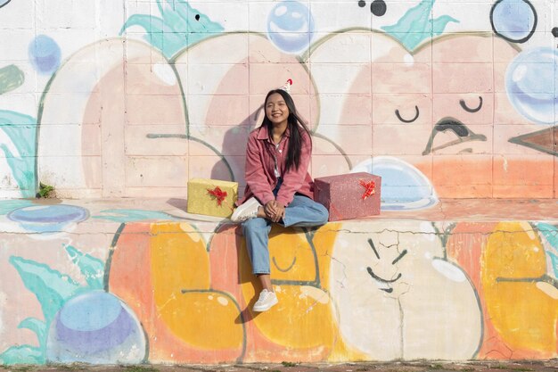 The cheerful girl wearing party hat with gift box sitting on colorful background