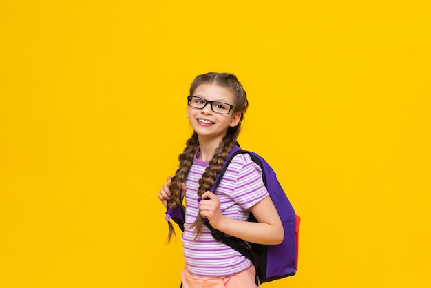 A cheerful girl with a bag on a yellow background