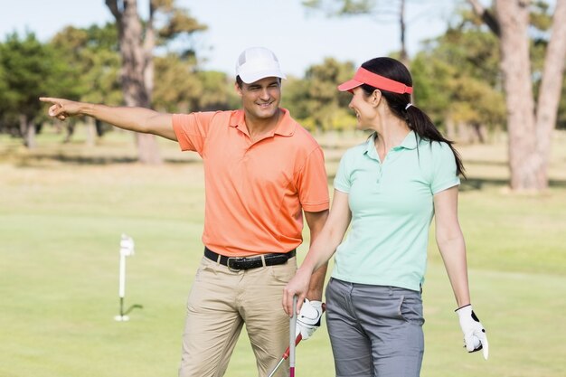 Cheerful golfer man pointing while standing by woman