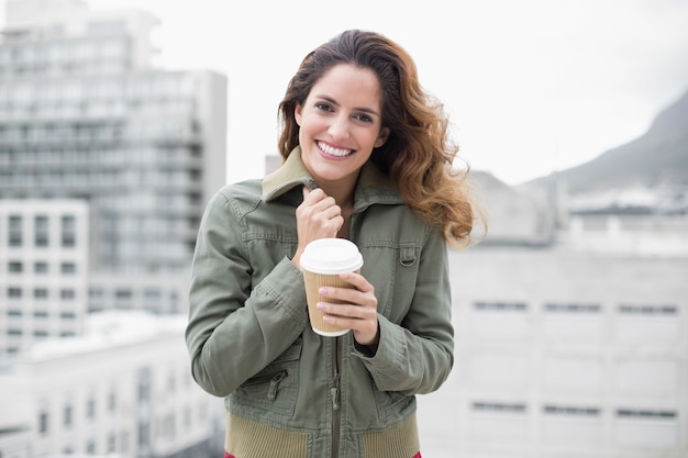 Cheerful gorgeous brunette in winter fashion holding disposable cup