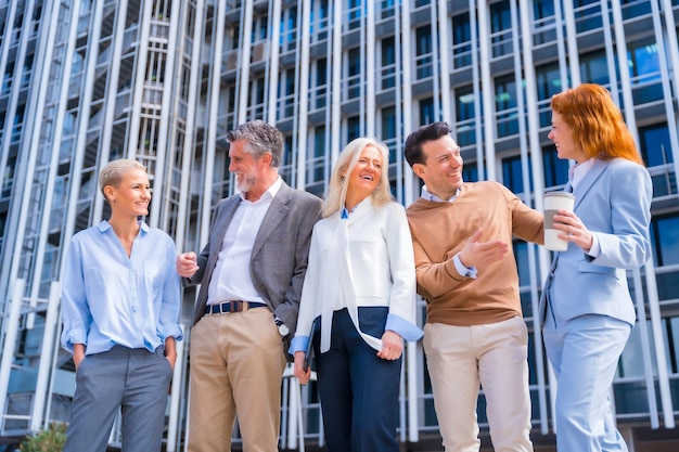 Cheerful group of coworkers outdoors in a corporate office area middleaged businesswoman and businessman