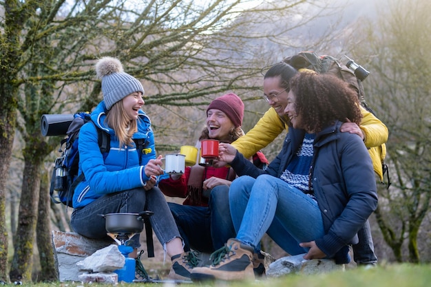 Cheerful group of young hikers take breakfast on the mountain Survival and adventure concept