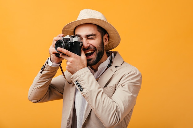 Cheerful guy in beige outfit takes photos on camera