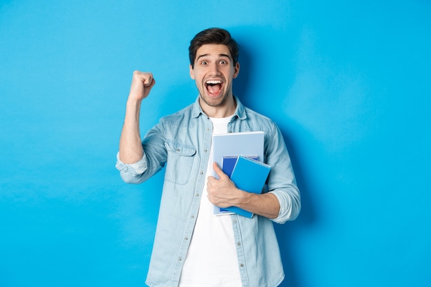 Cheerful guy holding notebooks and celebrating