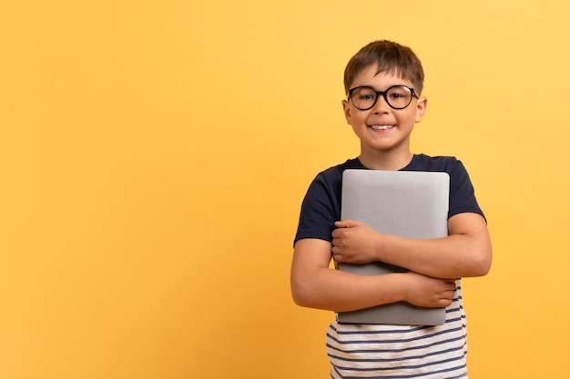 Cheerful guy school aged boy embracing computer laptop