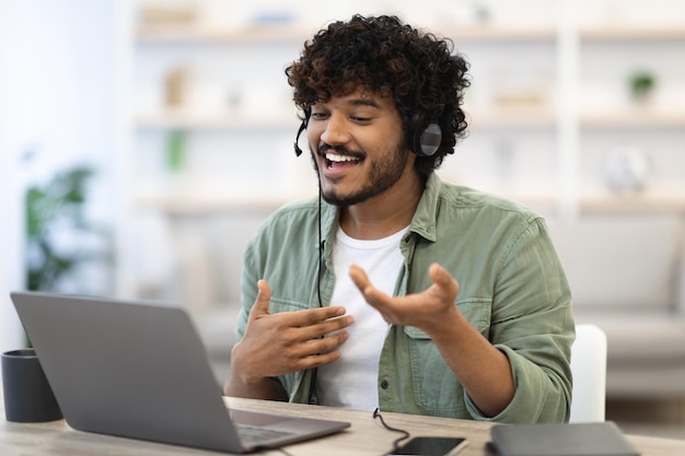 Cheerful handsome indian guy working online having video conference