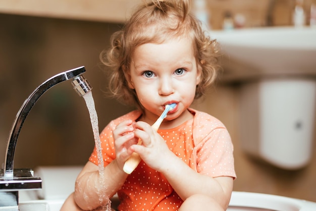 Cheerful happy child brushes his teeth in the morning in the bath