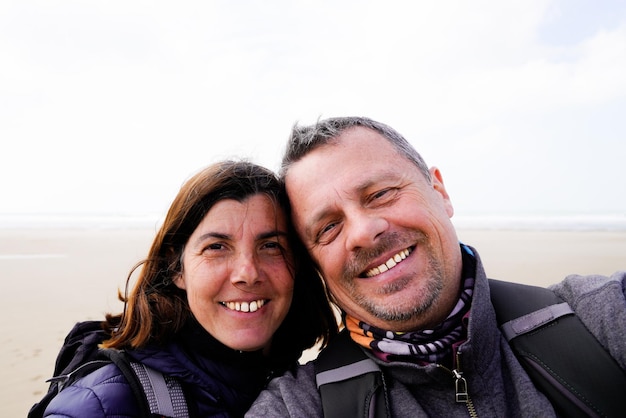 Cheerful happy tourist couple taking selfie in vacation on sand beach sea