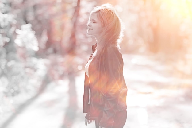 Cheerful happy young adult girl in sunlight rays and wind hair