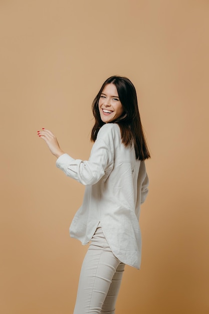 Cheerful happy young beautiful girl looking at camera smiling laughing over beige background