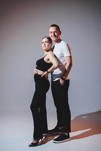 Cheerful happy young couple hugging on a plain background A stylish man and a woman in love are tenderly embracing