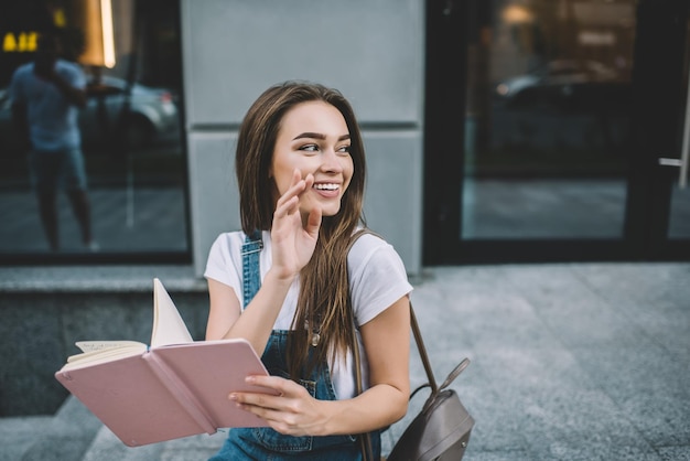 cheerful hipster girl in casual apparel smiling looking away waiting friend at city urban setting