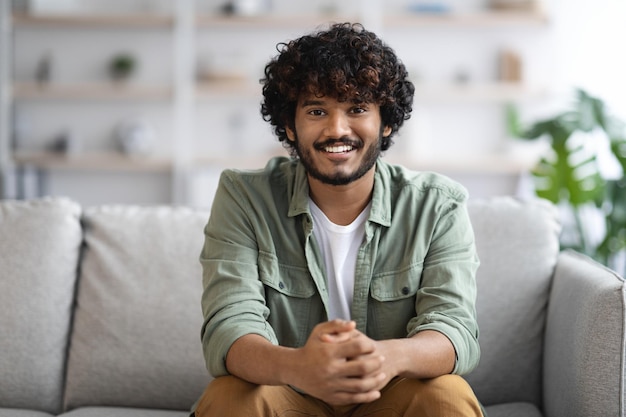 Cheerful indian guy posing on couch at home