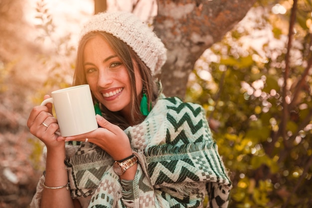 Cheerful lady with mug in forest