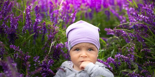 Cheerful little baby boy sitting in purple flowers