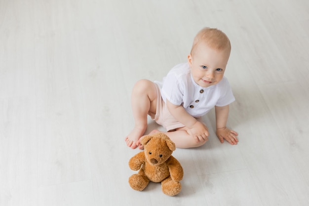 cheerful little boy playing with teddy bear on floor, space for text, banner, health, card