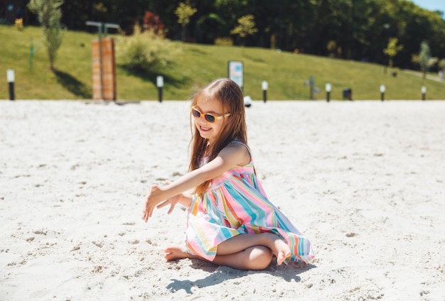 Cheerful little girl with down syndrome in a summer hat on the beach