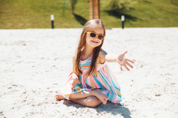 Cheerful little girl with down syndrome in a summer hat on the beach