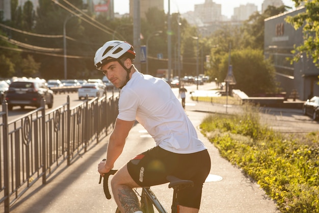 Cheerful male cyclist looking over his shoulder while riding bicycle in the city