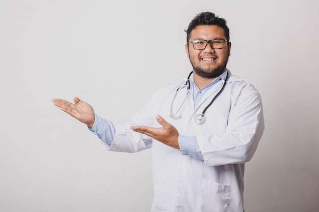 Cheerful male doctor presenting sideways isolated on white background with copy space