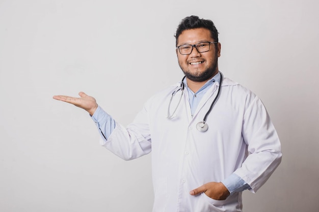 Cheerful male doctor presenting sideways isolated on white background with copy space