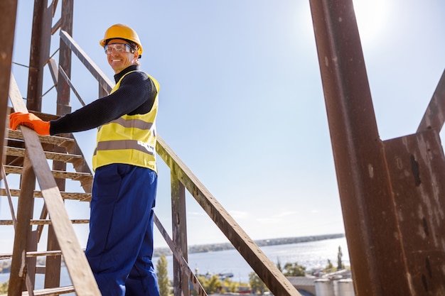 Cheerful male engineer standing on stairs outdoors