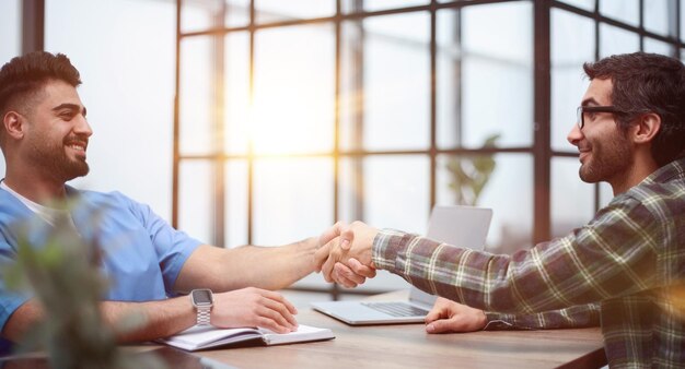 Cheerful male patient and doctor shaking hands