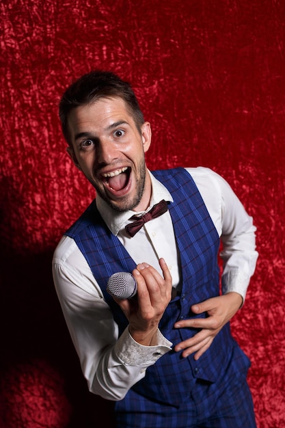 Cheerful male singer with microphone and in suit looking at camera