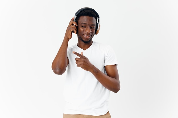 Cheerful man of African appearance listens to music with headphones emotions light background