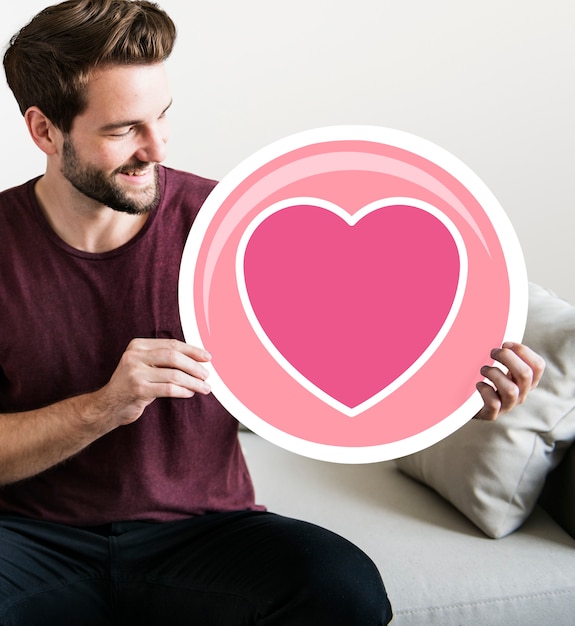 Cheerful man holding heart icon