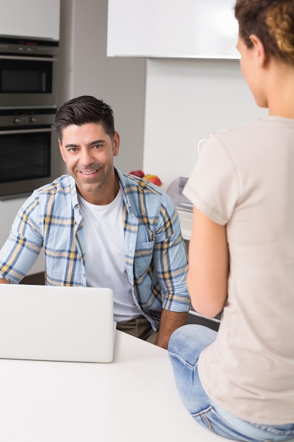 Cheerful man using laptop while partner sits on counter