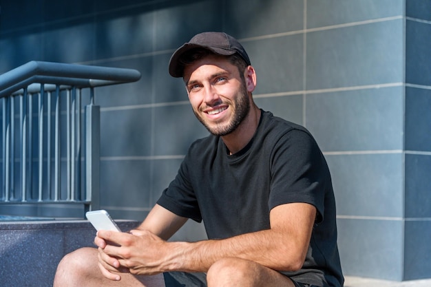 Cheerful man using smartphone on steps