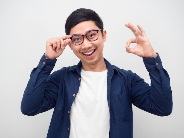 Cheerful man wearing glasses touch his glasses and make hand ok portrait white background